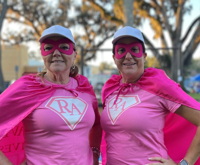 Two women superheros in pink capes